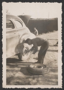 [Kierowca Borejszy zmienia koło do samochodu osobowego]