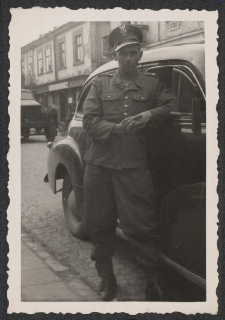 [Kapral Ludowego Wojska Polskiego przy samochodzie osobowym]
